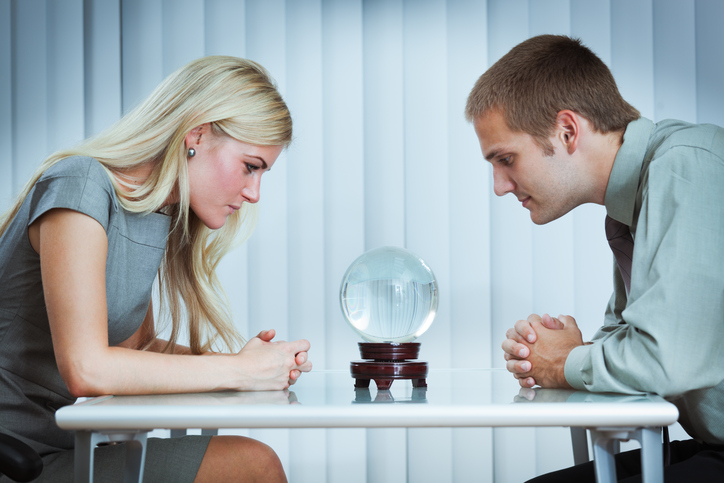 "Subject: A businessman and business woman, starring at a crystal ball looking for an outlook for future and fortune."